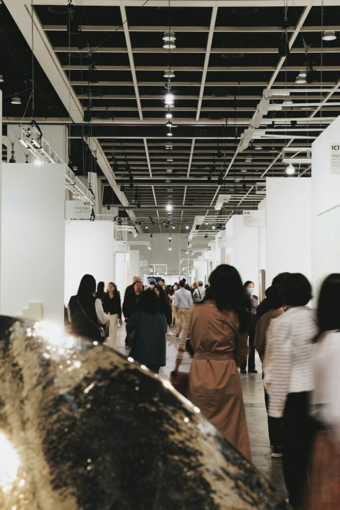 Visitors walking through a bright gallery hall lined with artwork