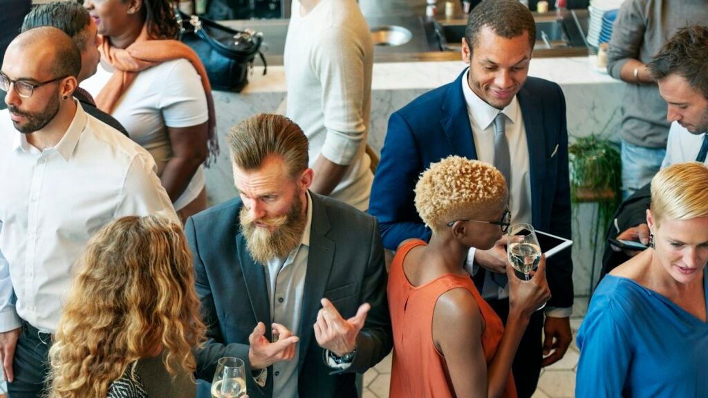 People chatting with drinks at a busy indoor networking event